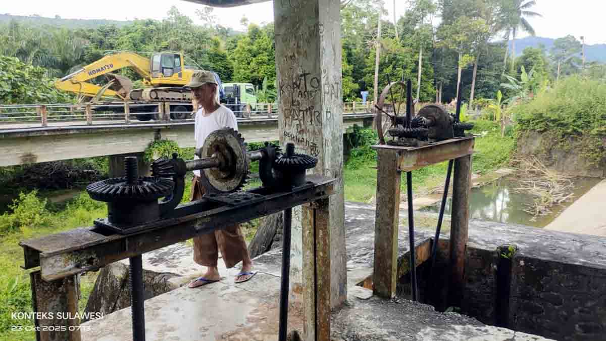 Sebuah alat berat jenis ekskavator tampak melintas di jembatan dekat Bendungan Sigenti Barat, Kecamatan Tinombo Selatan, Parimo, menuju lokasi tambang ilegal di Desa Sipayo, Kamis (23/10/2025). Penjaga pintu air setempat menutup akses demi mencegah kerusakan lebih parah pada bendungan dan saluran irigasi pertanian. Foto: Tommy Noho.