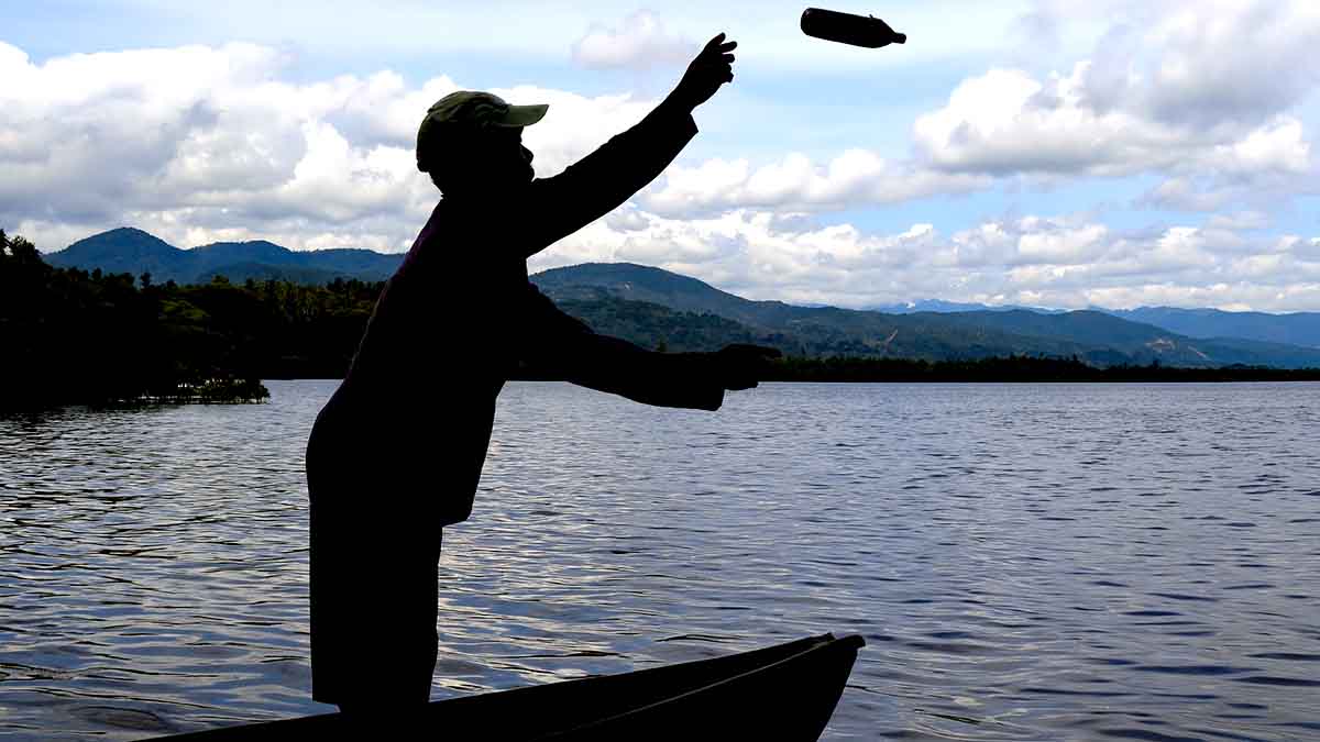 Keterangan Foto: Ilustrasi seorang pria melempar benda ke laut di perairan Sigenti, Parigi Moutong. Aksi ini menggambarkan maraknya praktik pengeboman ikan yang merusak ekosistem pesisir Teluk Tomini. Foto: Dok. Konteks Sulawesi
