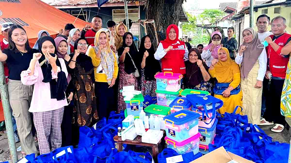 Keterangan Foto: Sejumlah warga dan mahasiswa terdampak kebakaran Asrama Parimo berpose bersama relawan PMI saat penyaluran bantuan sandang, pangan, obat-obatan, serta hygiene kit di lokasi pengungsian di Jalan Yojokodi, Palu. Berbagai paket bantuan terlihat tersusun di depan mereka, sementara para penerima menunjukkan gesture dukungan sebagai tanda semangat memulihkan kondisi pascabencana. Foto: Diskominfo