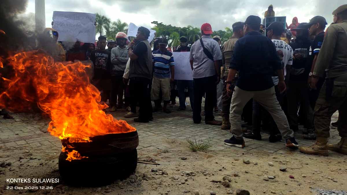 Keterangan Foto: Massa nelayan Teluk Tomini menggelar aksi damai di halaman Kantor Bupati Parigi Moutong, Parimo, dengan membakar ban sebagai simbol protes atas pemutusan rumpon dan aktivitas Survei Seismik 3D di perairan Teluk Tomini, Senin (22/12). Aksi berlangsung tertib dengan pengawalan aparat, nelayan menuntut penghentian survei dan ganti rugi atas kerugian yang dialami. Foto: Tommy Noho